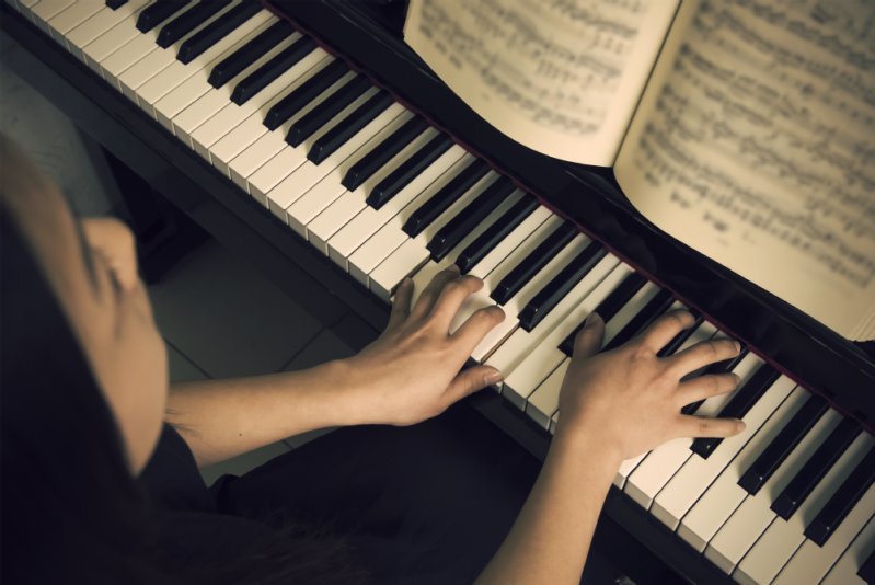 Ausschnitt eines bespielten Klaviers mit Notenheft